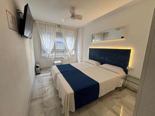 加的斯伊马尔旅馆的一间卧室配有一张带蓝白色毯子的床