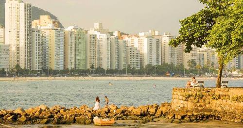 瓜鲁雅Apartamento Na Praia Das Astúrias的一群人,在海滩上靠近水面