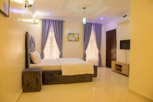 拉各斯House 4 Guest House & Apartments的一间卧室配有一张带紫色窗帘的床和一台电视。