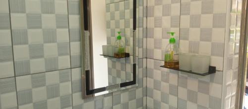 GuluHotel Judith Laroo的浴室设有镜子,墙上装有两瓶