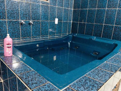 坎皮纳斯Hostel família Campineira的铺有瓷砖的浴室内的蓝色浴缸,配有粉红色的瓶子