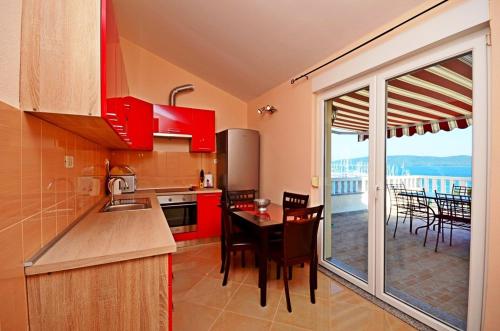 卡什泰拉Apartment Luxury Cream的一间带红色橱柜和桌子的厨房以及一个阳台