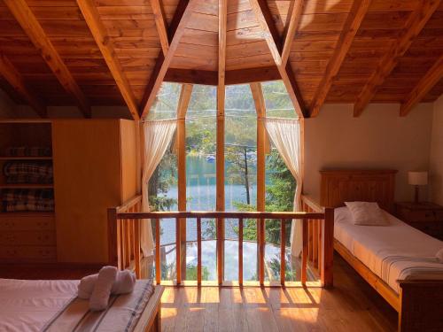 拉安戈斯图拉镇BOG Le Pommier - Cabañas con vista al lago y piscina climatizada的一间卧室设有两张床和大窗户