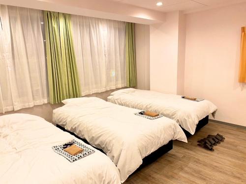 东京神保町樱花酒店的带绿色窗帘的客房内的三张床