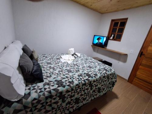 坎波斯杜若尔当Pousada Lofts e Suítes Campos的一间卧室配有一张床和一张桌子上的电视