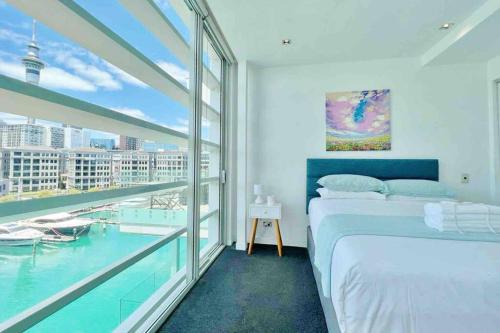 奥克兰Waterfront Apartment with Sky tower & Harbour View的一间卧室设有一张床和一个大窗户