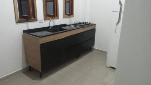 卡纳内亚Cantinho do Sossego - kitnets的厨房配有水槽和冰箱