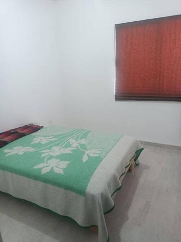 GómezExcelente hogar para descansar的床上铺有绿色和白色的毯子