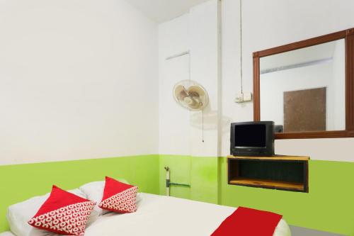 JodohOYO 91344 Wr House Syariah Batam的一间卧室配有一张带红色枕头的床和一台电视。