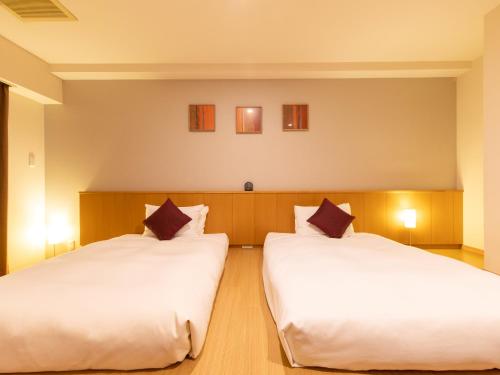 东京门前仲町东急酒店的配有白色床单的客房内的两张床