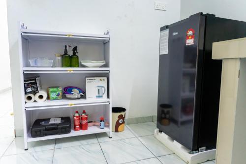 麻坡Tok Umi Guesthouse@AMJ Bakri的架子旁边的房间里放着一台小冰箱
