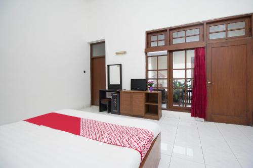TimuranSuper OYO 759 Hotel Dewi Sri的一间卧室配有一张床、一扇门和电视