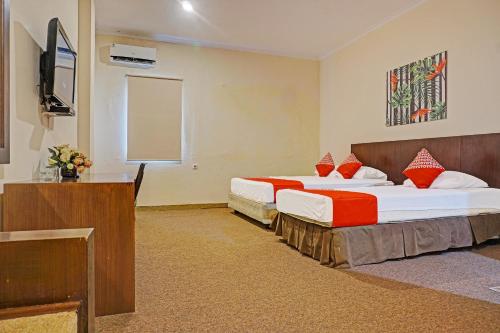 马卡萨Collection O 91414 Hotel Marina Beach的酒店客房设有两张床和电视。