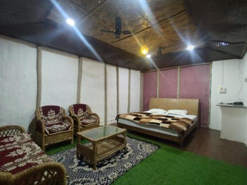 BokākhātAVA Resort, Kaziranga的配有床和两把椅子及一张桌子的房间