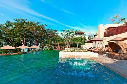 普吉镇The Westin Siray Bay Resort & Spa, Phuket的度假村的游泳池配有桌子和遮阳伞