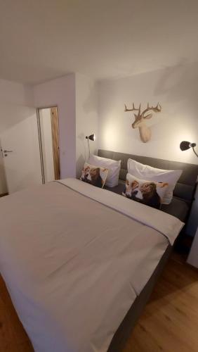 博尔斯特尔朗Ferienwohnung Bergblume的一张带枕头的大型白色床和墙上的鹿头