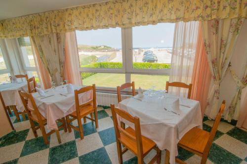 阿霍Hotel Costa de Ajo的一间带两张桌子和大窗户的用餐室