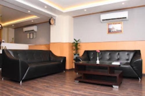 因帕尔Hotel Yaiphabaa , Imphal的客厅配有黑色真皮沙发和桌子