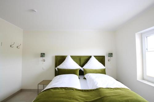 诺德代希Seeblick 1的一间卧室配有带绿色和白色枕头的床