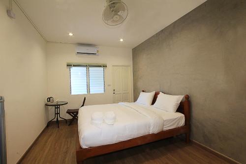 波普托ZAYN Samui Hotel的一间卧室配有一张带白色床单和一张桌子的床。