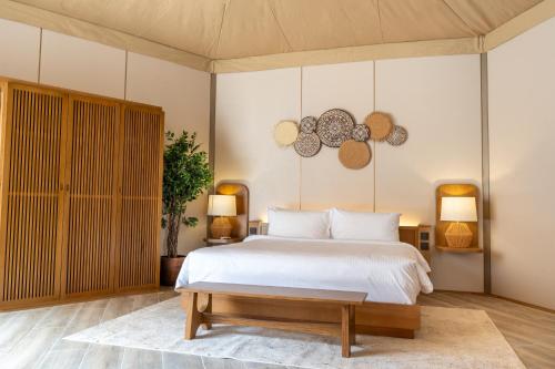 艾恩Pura Eco Retreat, Jebel Hafit Desert Park的卧室配有白色的床和两盏灯。