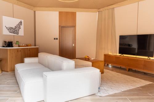 艾恩Pura Eco Retreat, Jebel Hafit Desert Park的客厅配有白色沙发和电视