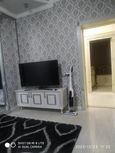 AndizhanАпартамент в центре города的客厅配有白色橱柜上的平面电视