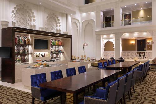 浦那Sheraton Grand Pune Bund Garden Hotel的一间配备有桌子和蓝色椅子的用餐室