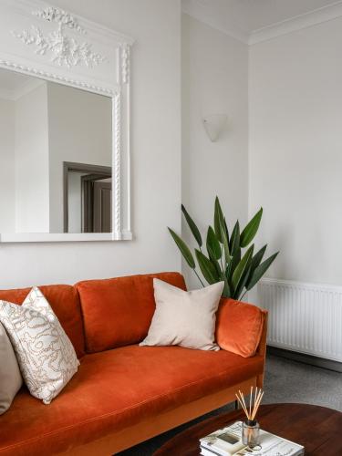 伦敦Urban Rest Notting Hill Apartments的客厅里一张橙色的沙发,配有镜子