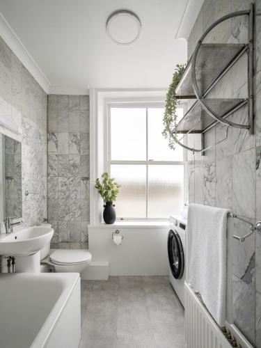 伦敦Urban Rest Notting Hill Apartments的浴室配有白色浴缸、水槽和洗衣机。