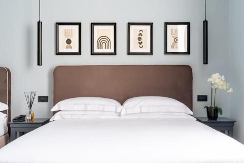 佛罗伦萨Flom Boutique Hotel的卧室配有一张白色床,墙上挂有4张照片