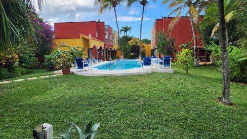 科苏梅尔Casa Colonial, Cozumel的一个带蓝色椅子的庭院内的游泳池