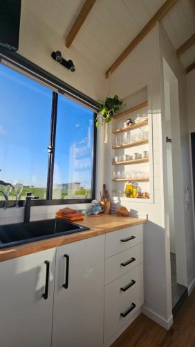 KillarneyCoastal Haven - Port Fairy Tiny Homes的厨房配有白色橱柜、窗户和水槽