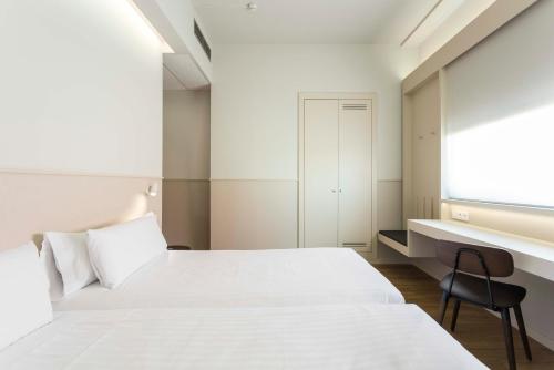 特拉萨Hotel Terrassa Confort的卧室配有白色的床和书桌