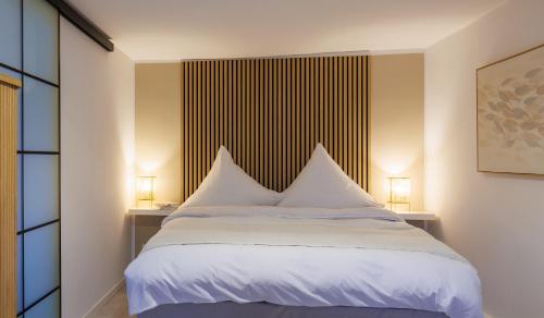 拜罗伊特Romantisches Apartment mit Whirlpool in Bayreuther Fußgängerzone的一间卧室配有一张带白色床单和两盏灯的床。