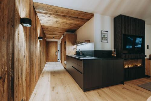 莱赫阿尔贝格Balma Restaurant Apart的厨房设有黑色的柜台和木制天花板。