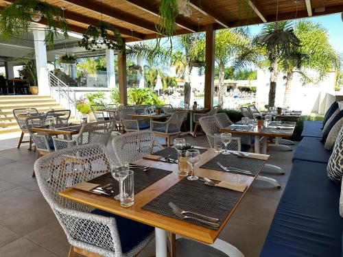 玛利亚Kyknos Beach Hotel & Bungalows的一间带木桌和桌椅的餐厅