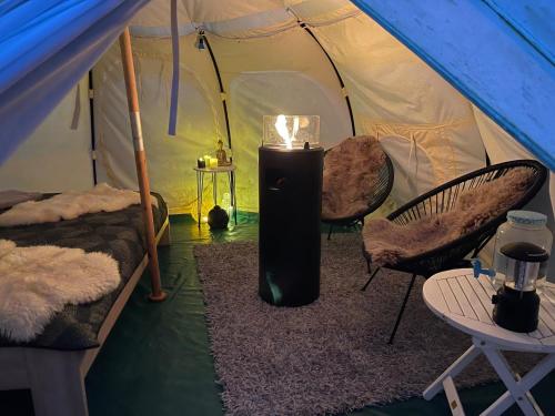 库克斯港NatureCamp Cuxhaven的帐篷配有两把椅子和加热器