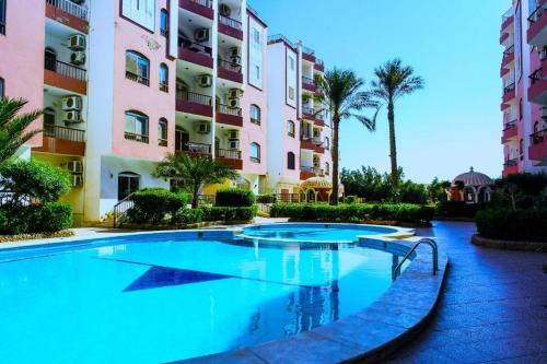 赫尔格达Desert Pearl Romantic Apartment的棕榈树建筑前的游泳池