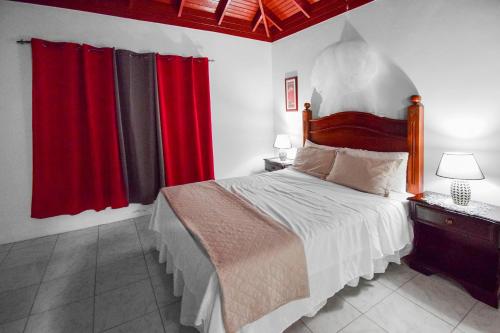 曼德维尔Harriott Heights的一间卧室配有一张带红色窗帘的大床