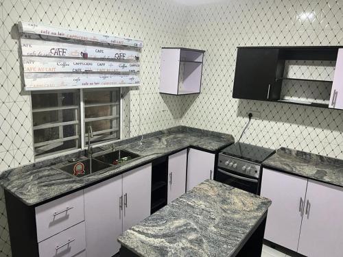 拉各斯Muniz Apartments的厨房配有白色橱柜、水槽和柜台。