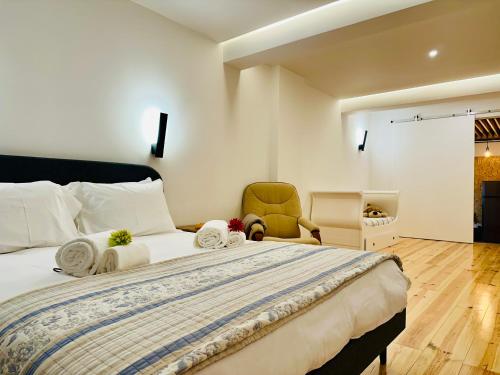 里斯本A casa na Estrela的一间卧室配有一张大床和一把椅子