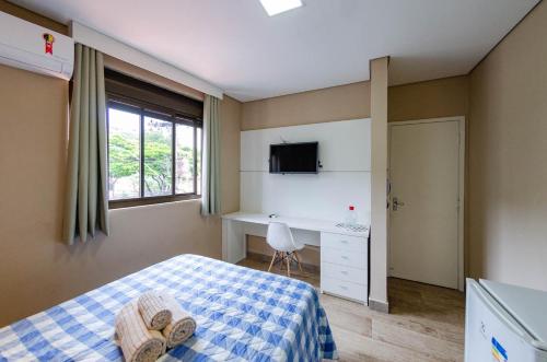 贝洛奥里藏特STUDIOS CORACAO EUCARISTICO的一间卧室配有一张床、一张书桌和一个窗户。