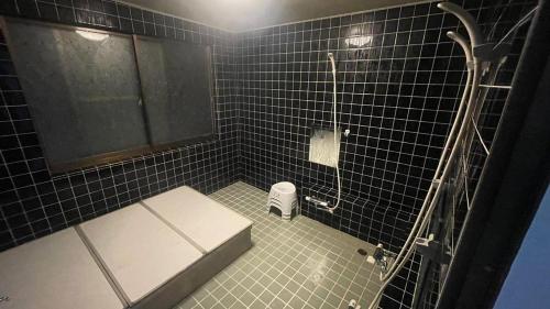 白马村Iimori Vista的黑色瓷砖浴室设有卫生间和淋浴。