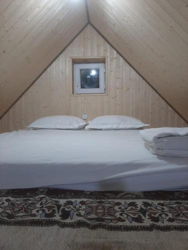 SatyEldos_Kolsai的阁楼上的一张白色大床,设有窗户