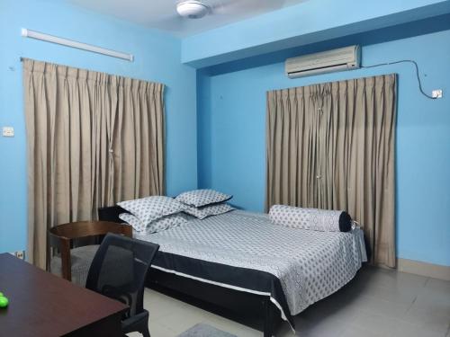吉大港Home Stay Chittagong的一间卧室配有一张蓝色墙壁的床和一张桌子