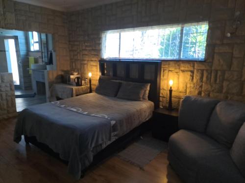 杰米斯顿Meadows Guesthouse的一间卧室配有一张床、一张沙发和一个窗口