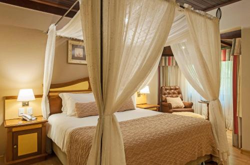 格拉玛多西拉角酒店的一间卧室配有一张天蓬床和一把椅子