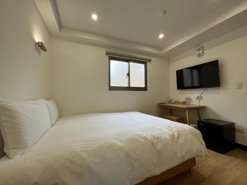 台北宏洲旅社HZ Hotel的卧室配有白色的床和平面电视。