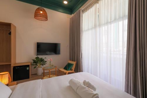 顺化Lemi - Homestay in Hue的卧室配有白色的床和电视